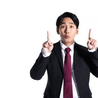 1+1＝？と驚いて上方向を指差すスーツ姿の男性の写真
