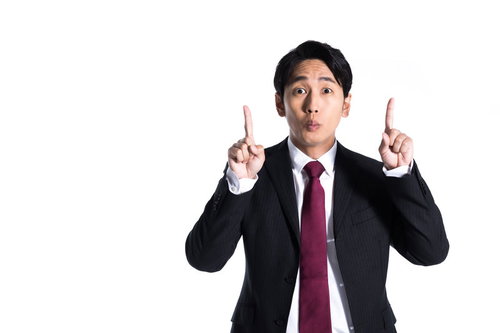 1+1＝？と驚いて上方向を指差すスーツ姿の男性