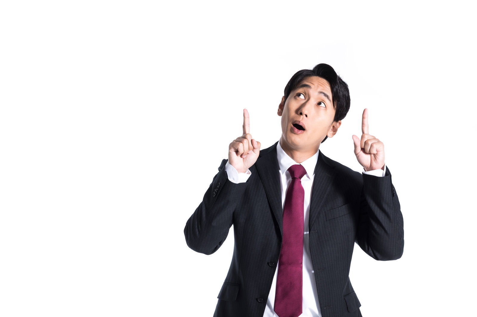 驚いた表情で上方向を指差すスーツ姿の男性［モデル：大川竜弥］