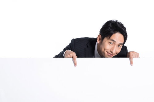 詳細はこちらからと白い看板の上から下を指さす販売員