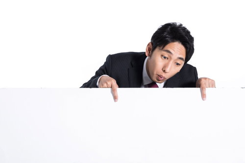 画面下のテロップを指さす黒いスーツの男性タレント