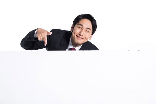 満面の笑みでスーツ姿の男性会社員が下を指さす