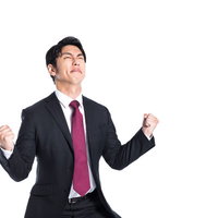 受注が決まって両手でガッツポーズをするスーツ姿の男性の写真