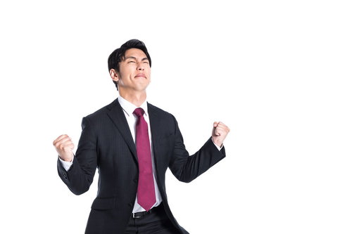 受注が決まって両手でガッツポーズをするスーツ姿の男性