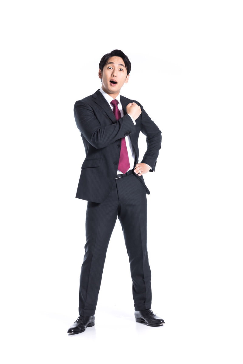 気合いを入れるポーズをとる紺色スーツの男性［モデル：大川竜弥］