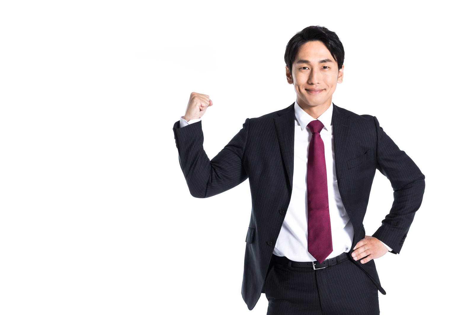 黒いスーツに赤いネクタイの男性が右手でガッツポーズ［モデル：大川竜弥］
