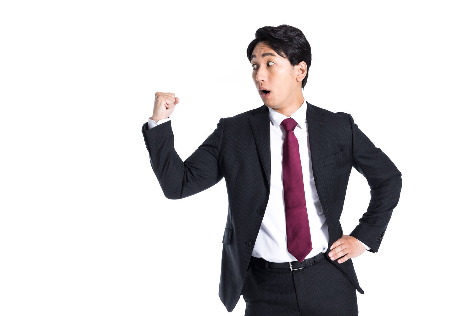 右手でガッツポーズをする紺色のスーツに赤いネクタイの男性［モデル：大川竜弥］