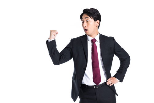 気づいたら拳を振り上げてたセルフパワハラ--ガッツポーズするスーツ姿の男性