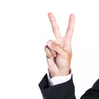 スーツ姿でピースサインを作る男性の指二本の写真