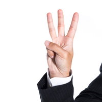 指三本を立てて数字の3を表現するビジネスマンの手の写真