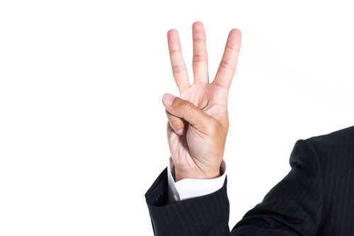 指三本を立てて数字の3を表現するビジネスマンの手