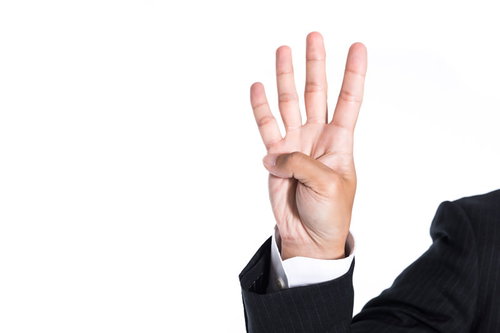 スーツ姿の男性が立てる4本の指のハンドサイン