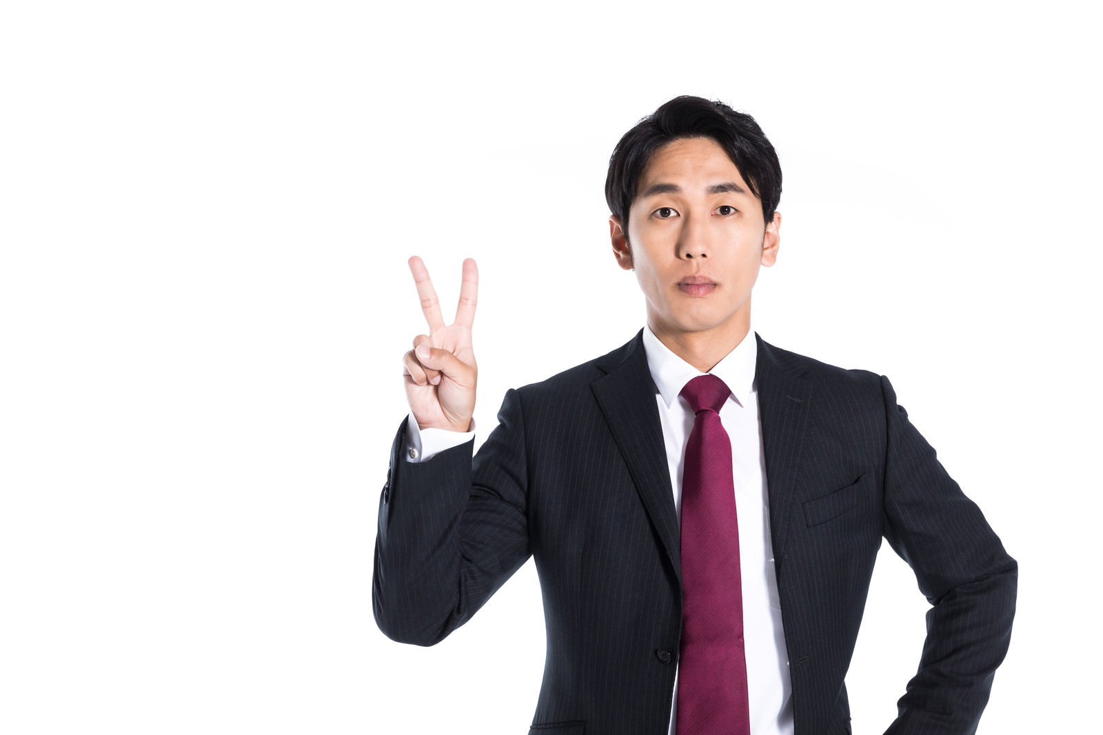 真顔で左手でピースサインをする紺色ストライプスーツ姿の男性、白シャツ、エンジ色ネクタイ［モデル：大川竜弥］