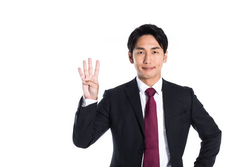 スーツ姿で4番を指さす男性のポーズ