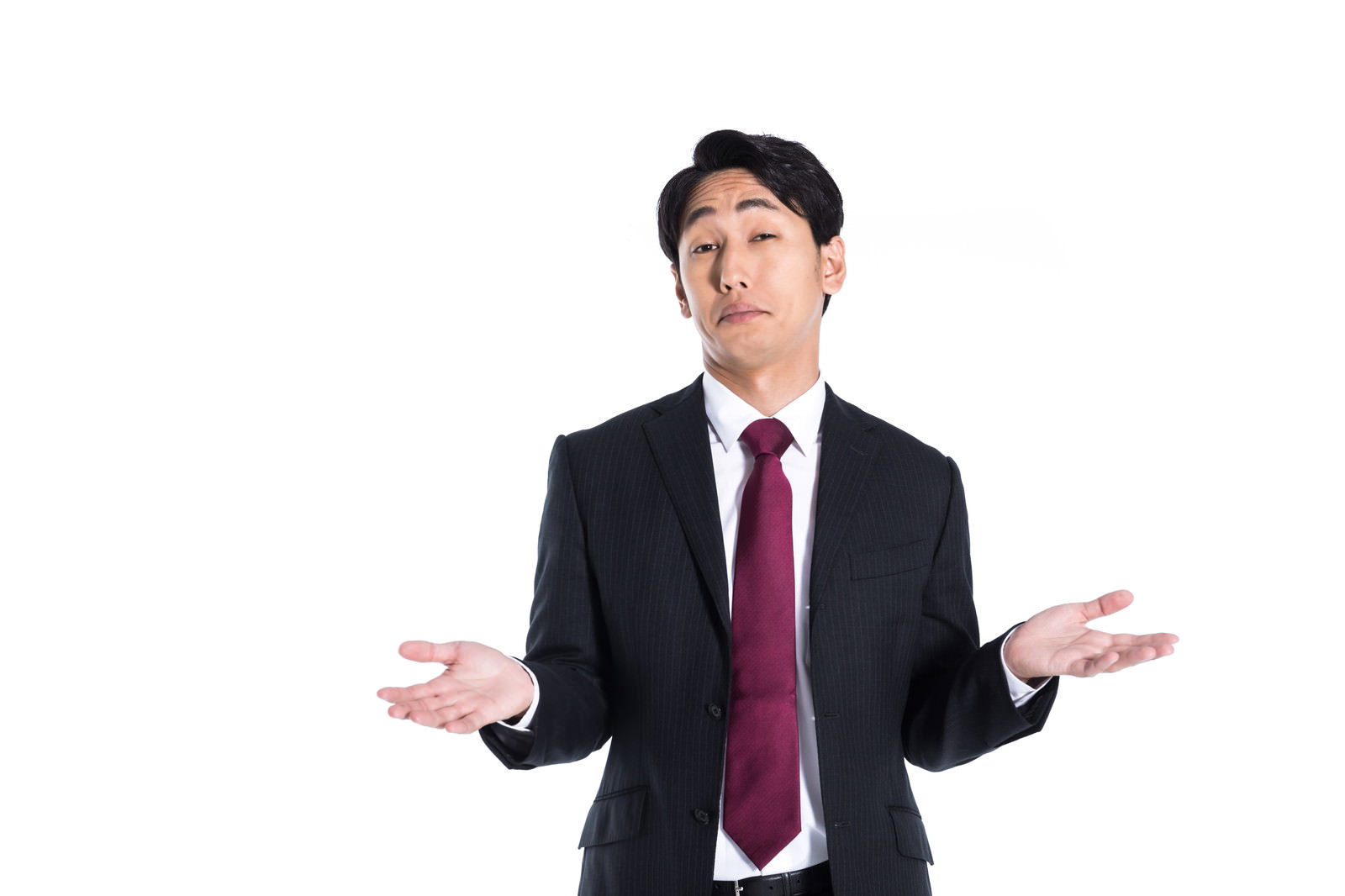 赤いネクタイのスーツを着た男性が両手を広げて困惑している様子［モデル：大川竜弥］