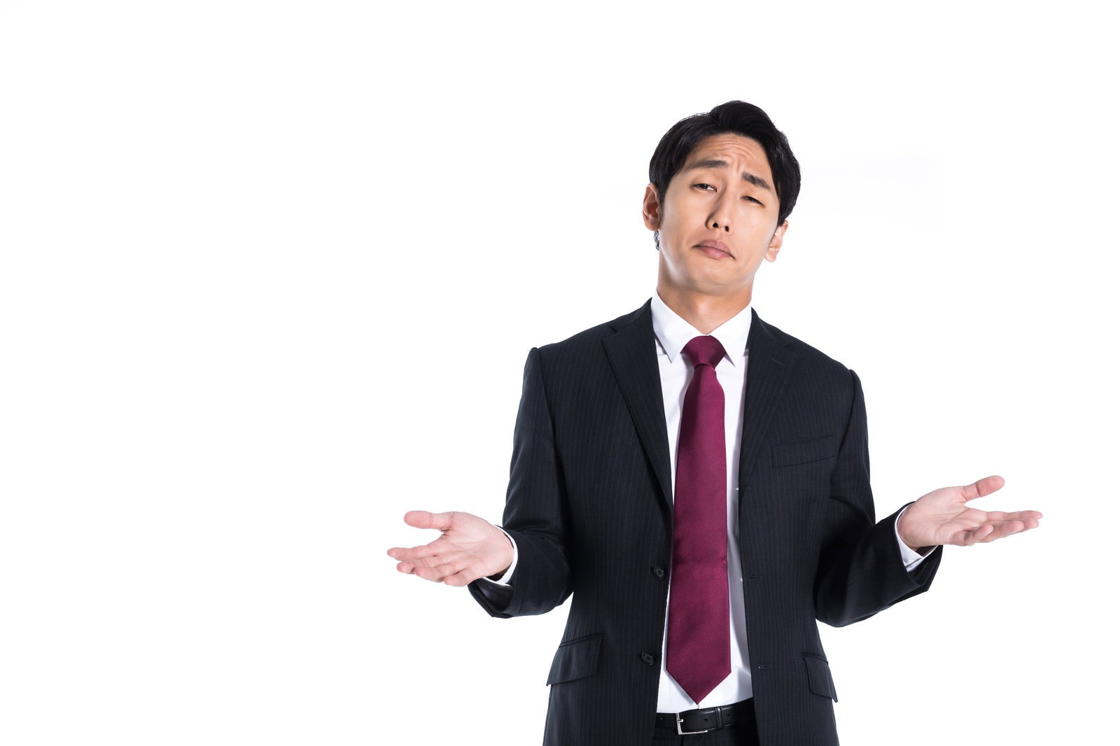 両手を広げて困った表情で上を見上げるスーツ姿の男性［モデル：大川竜弥］