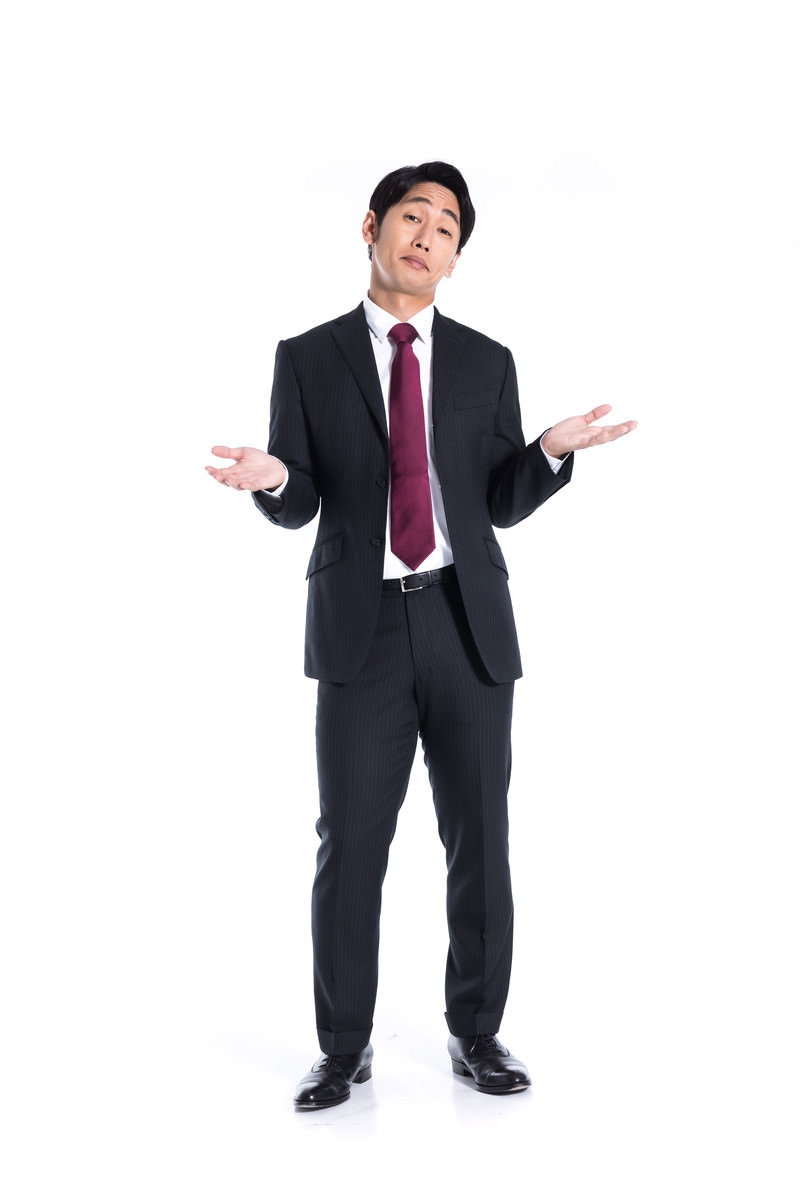 黒いスーツ姿の男性が両手を上に広げて視線を上向けている、困惑を示すポーズ［モデル：大川竜弥］