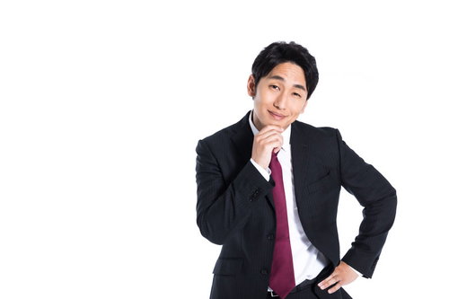 紺色のスーツに赤いネクタイの会社員が浮かべる不敵な笑み