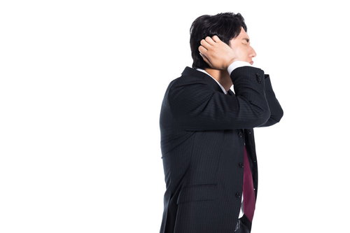 失敗して頭を抱えて耳を塞ぐ困惑したスーツ姿の会社員男性