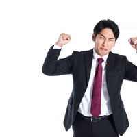 強面で拳を振り上げて悔しがる会社員、激怒の表情の写真