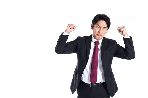強面で拳を振り上げて悔しがる会社員、激怒の表情