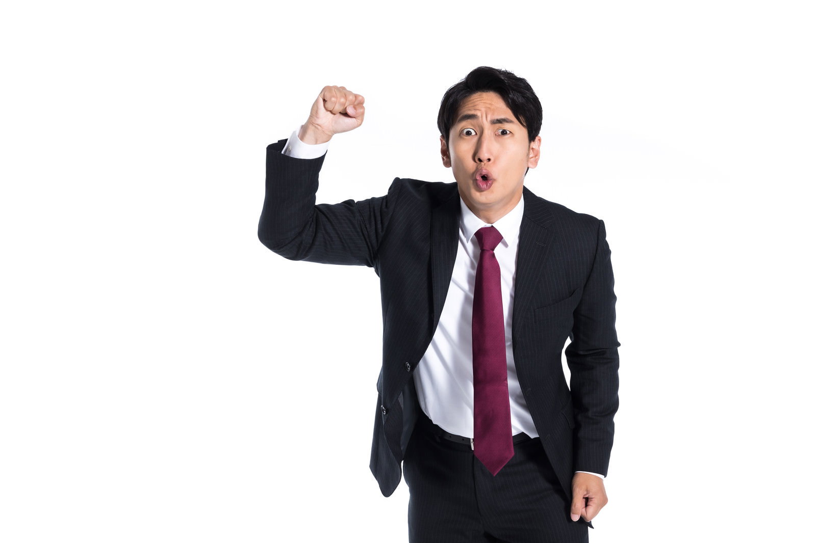 拳を振り上げて激しく怒る表情のスーツ姿の会社員男性［モデル：大川竜弥］