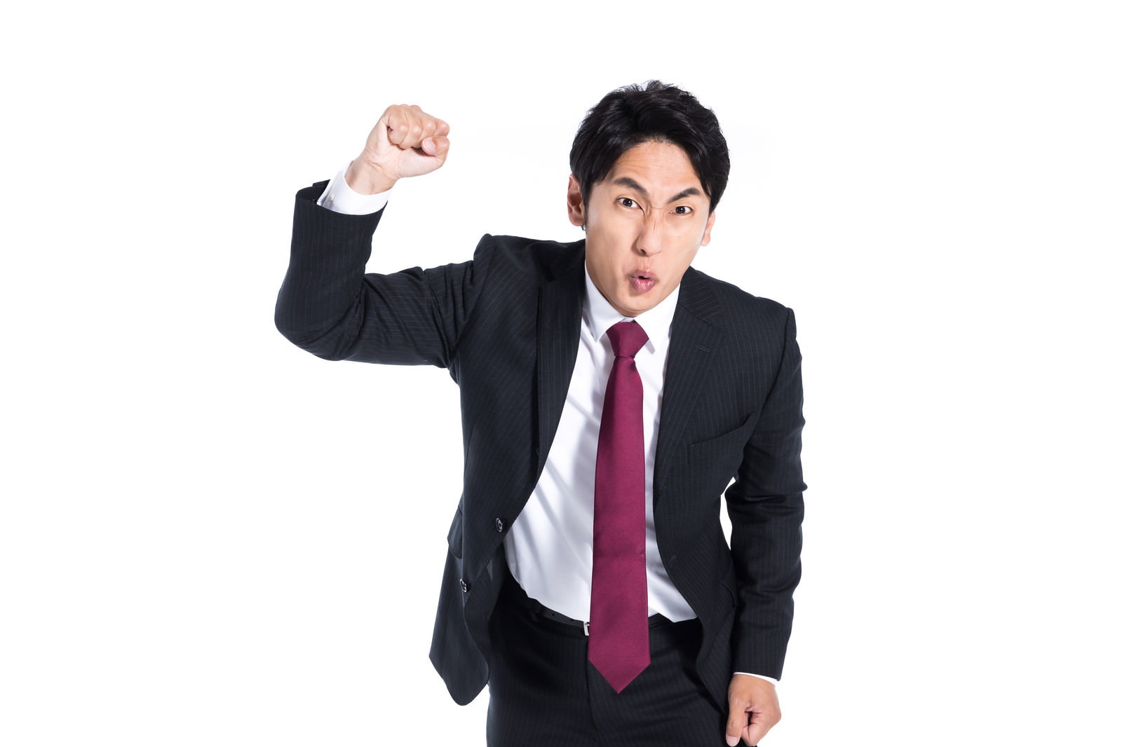 拳を振り上げて怒りの表情を見せる濃紺スーツの会社員男性［モデル：大川竜弥］