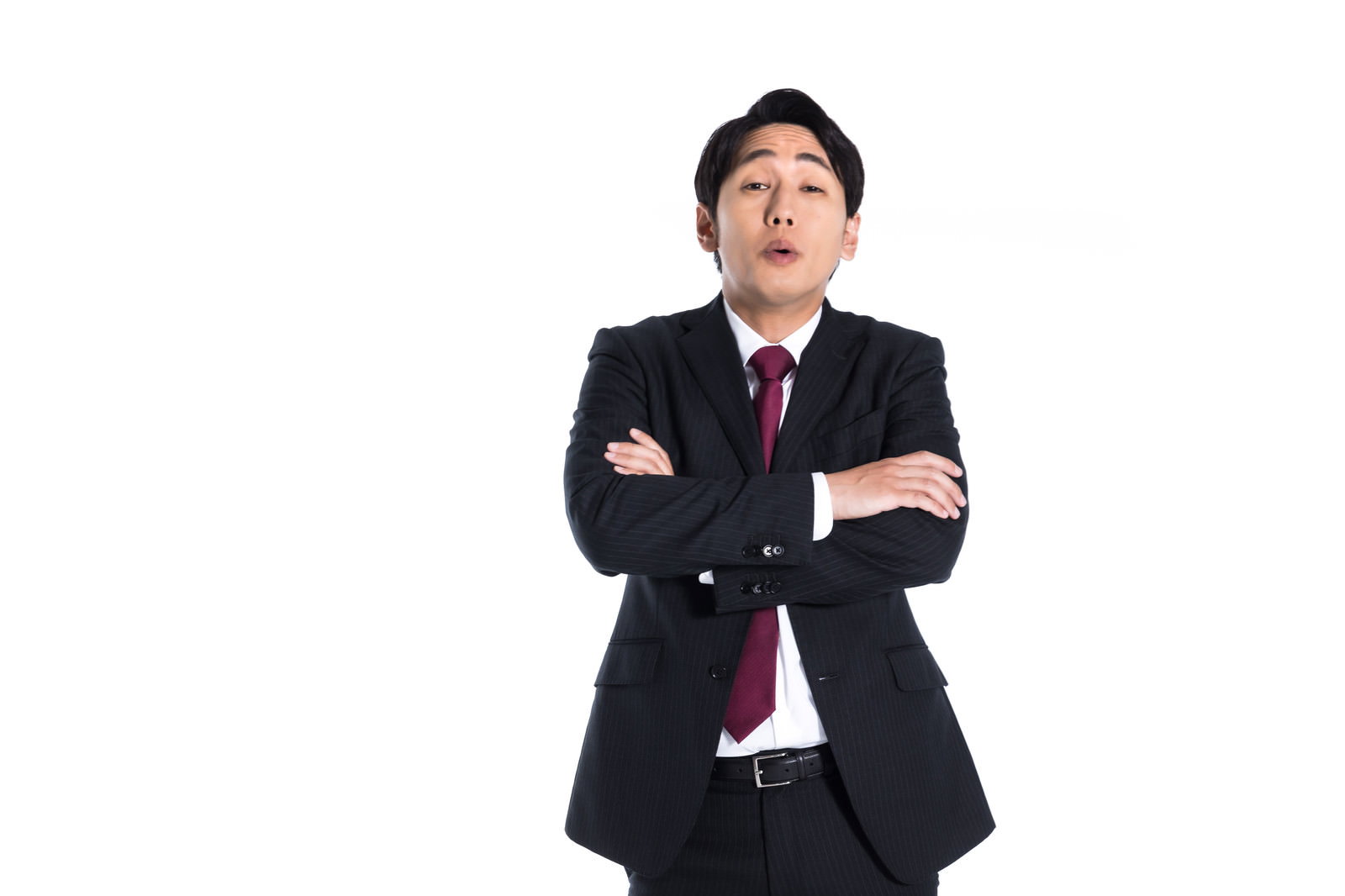 腕組みをして見下すような表情で立つスーツ姿の上司［モデル：大川竜弥］