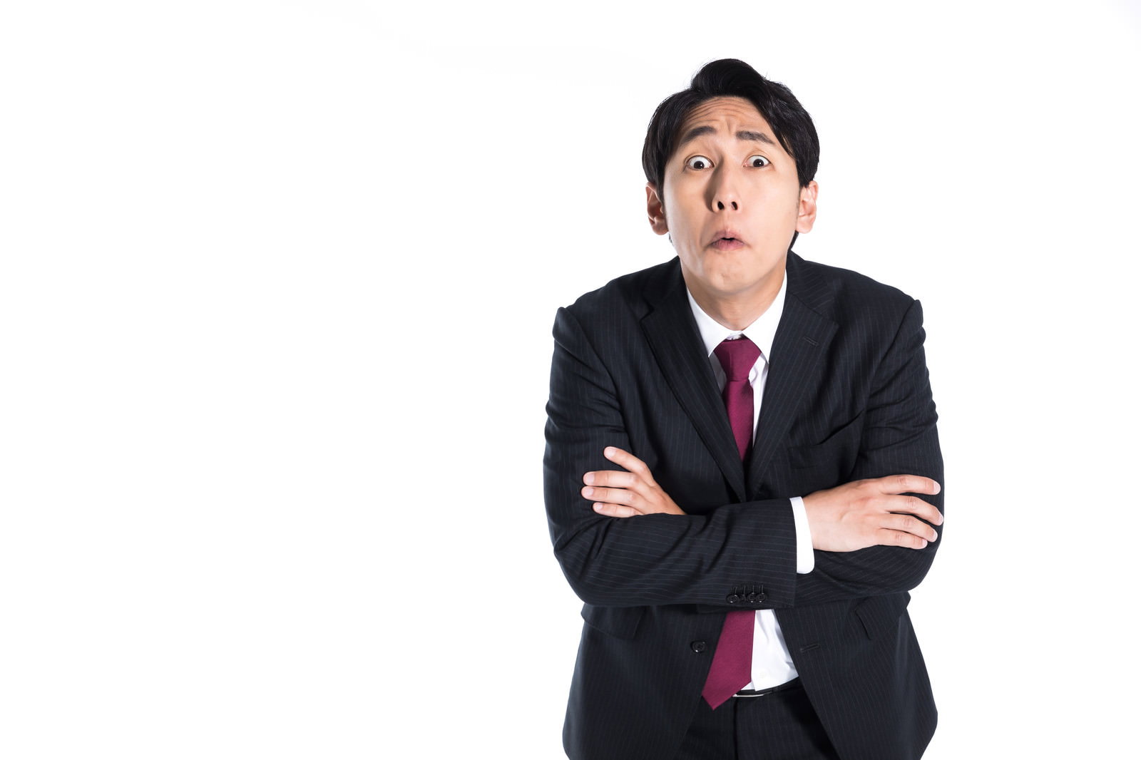腕を組んで見上げる怒った表情のスーツ姿の男性［モデル：大川竜弥］