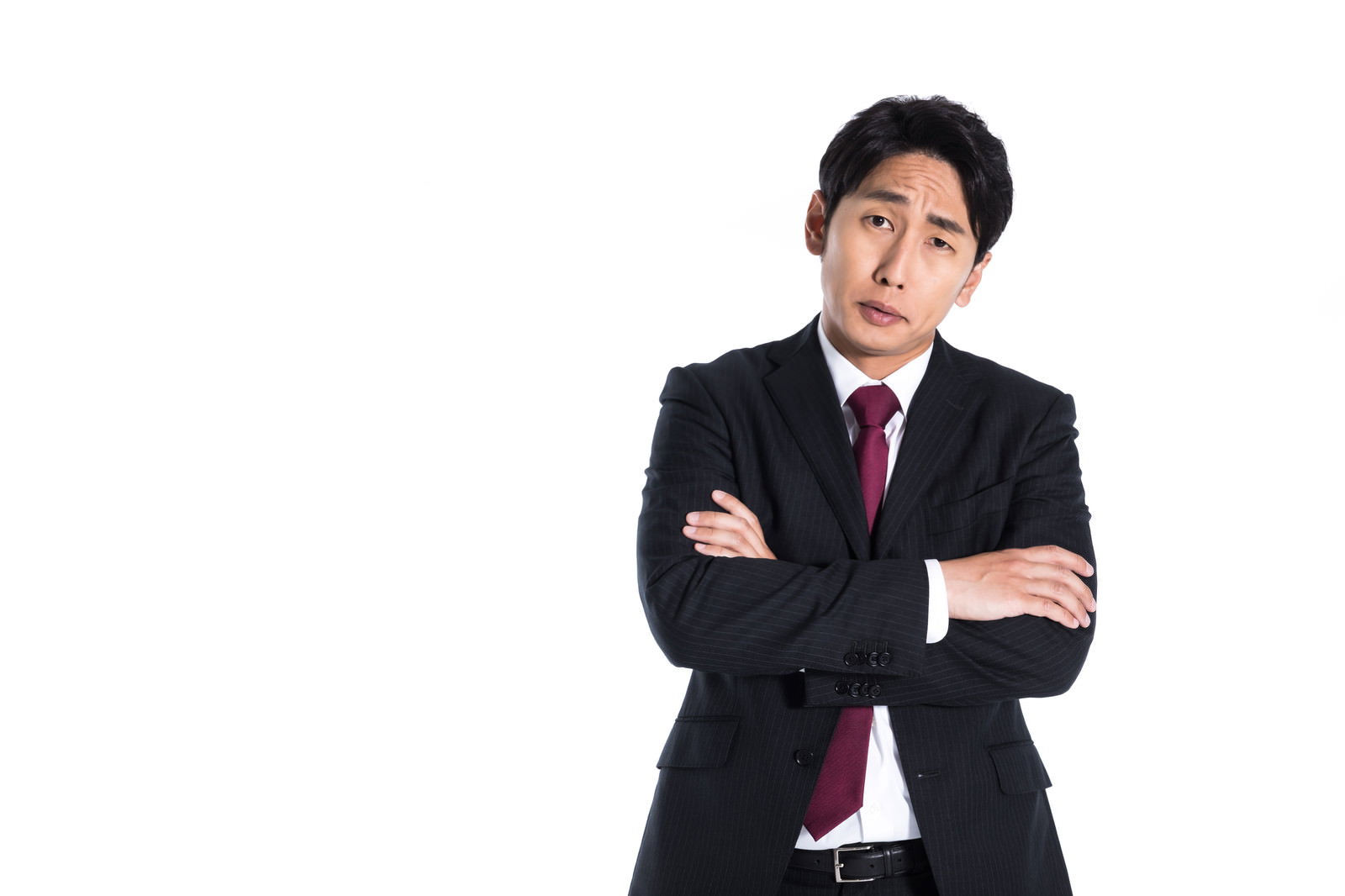 腕組みして偉そうな表情を浮かべるダークスーツの男性［モデル：大川竜弥］
