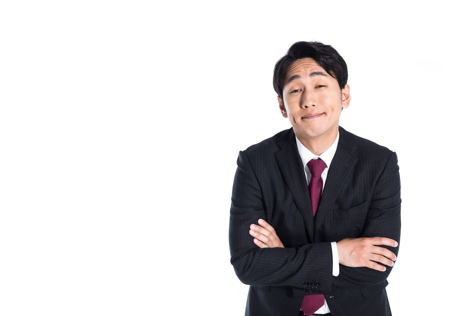 腕組みをして呆れた表情を浮かべる黒いスーツ姿のビジネスマン［モデル：大川竜弥］