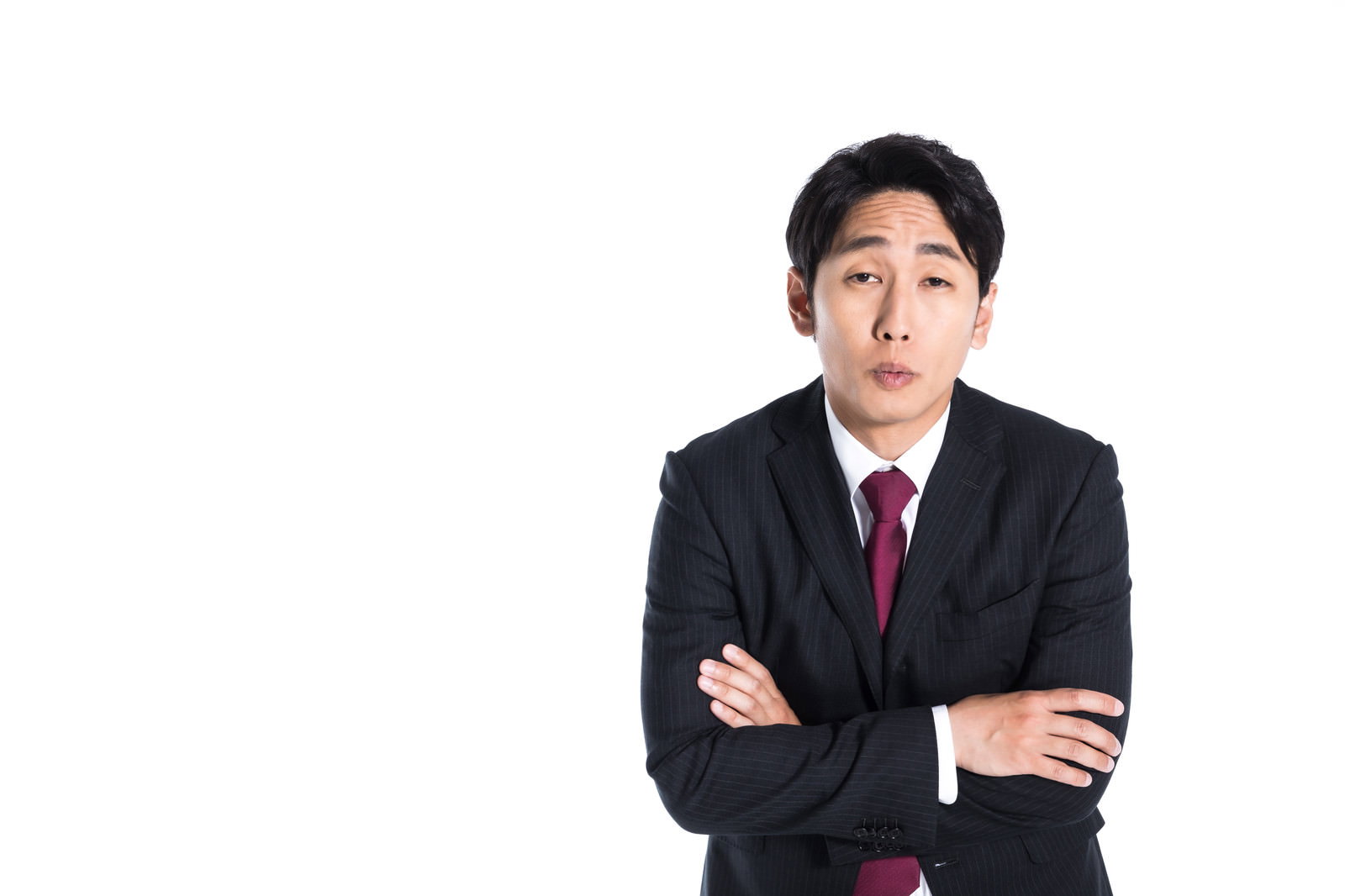 腕組みして上方を見つめるスーツ姿の男性［モデル：大川竜弥］