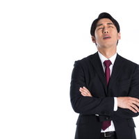 腕を組んで頭を抱える途方にくれるスーツ姿の男性の写真