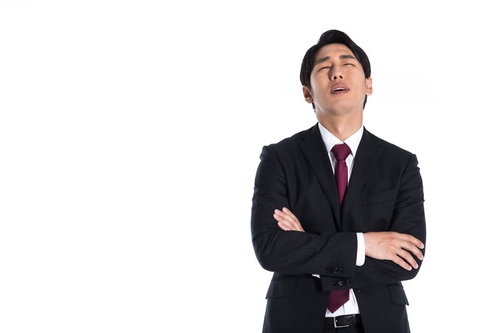 腕を組んで頭を抱える途方にくれるスーツ姿の男性