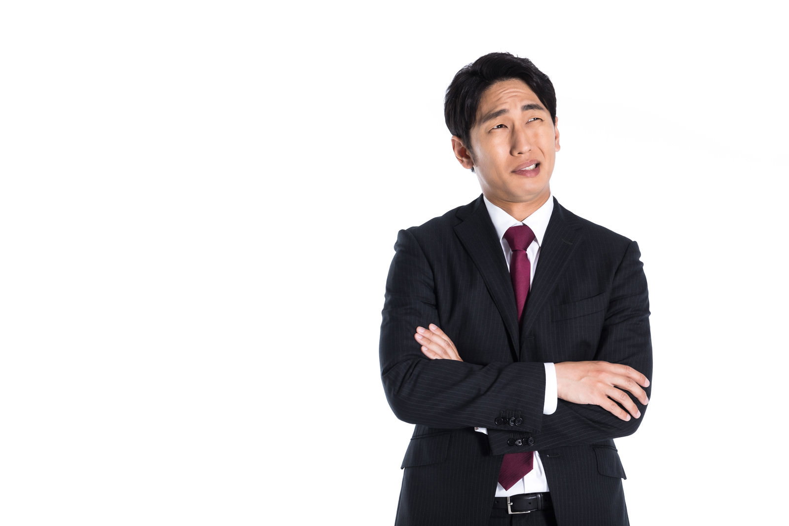 腕を組み上を見つめ考え込むスーツを着た男性