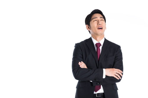 腕を組んで上を向く困った表情のスーツ姿男性