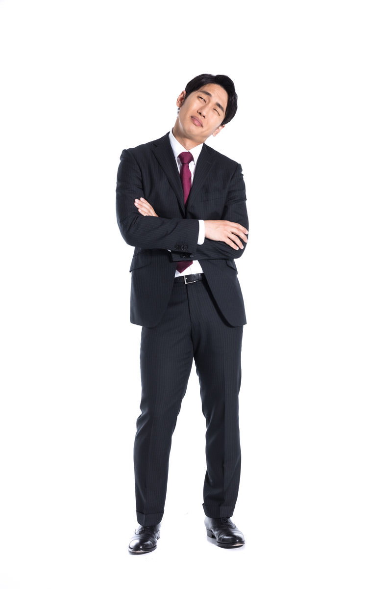 黒いストライプ柄スーツを着た男性が両腕を組み、上を向いて考え込んでいる［モデル：大川竜弥］