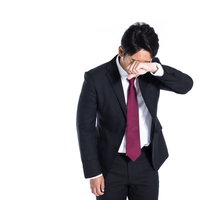 職場で悔し泣きする営業マンの写真