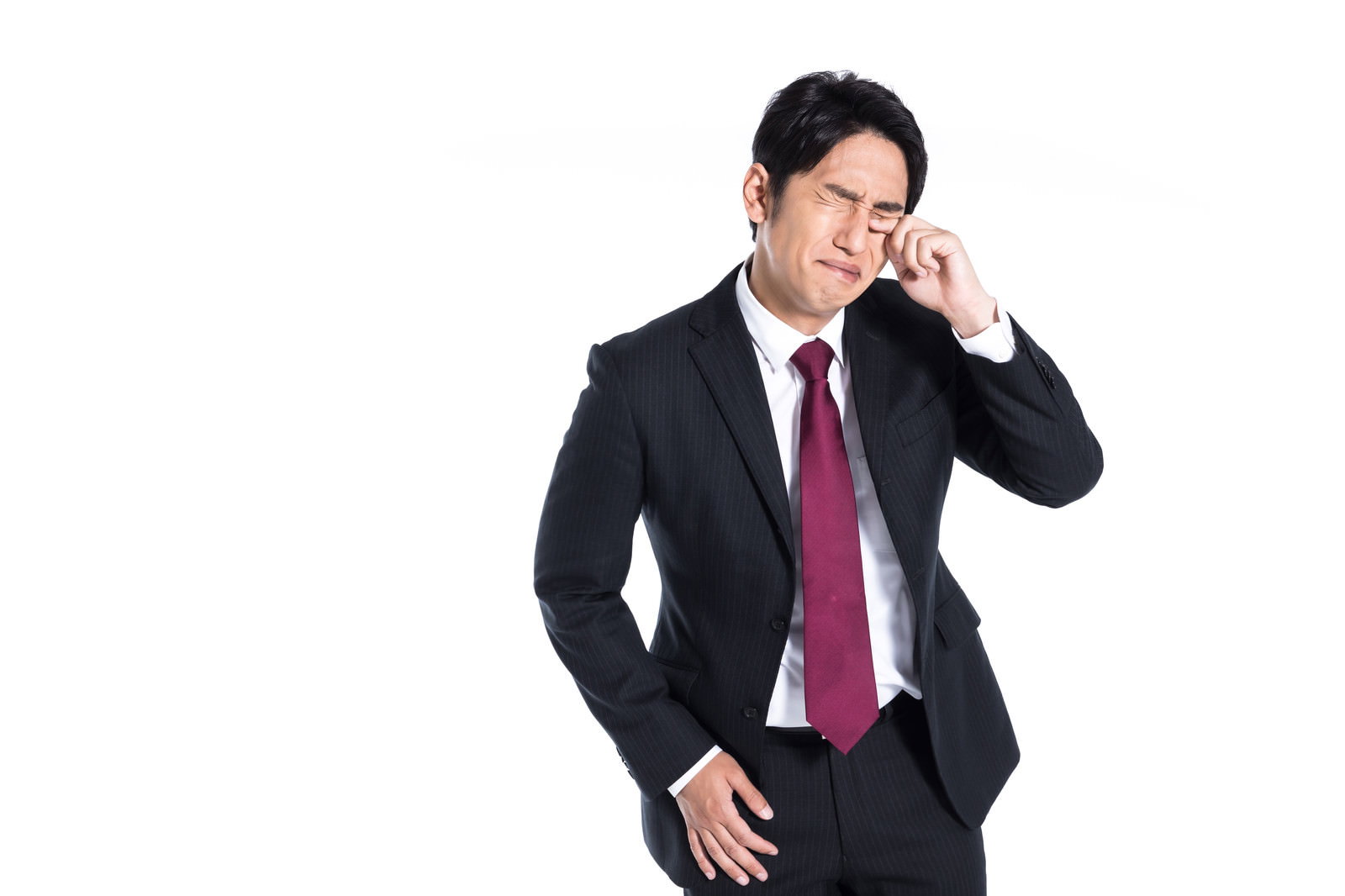 黒いスーツを着た男性が片手で頭を抱えて悩んでいる様子［モデル：大川竜弥］