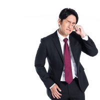 左目のゴロゴロが気になる会社員男性のストレス表現の写真