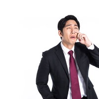 寝不足で疲労困憊する営業マンの悔し泣きと後悔の写真