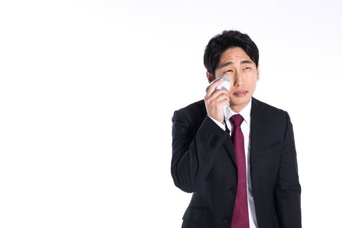 スーツ姿の男性がハンカチで涙を拭く姿