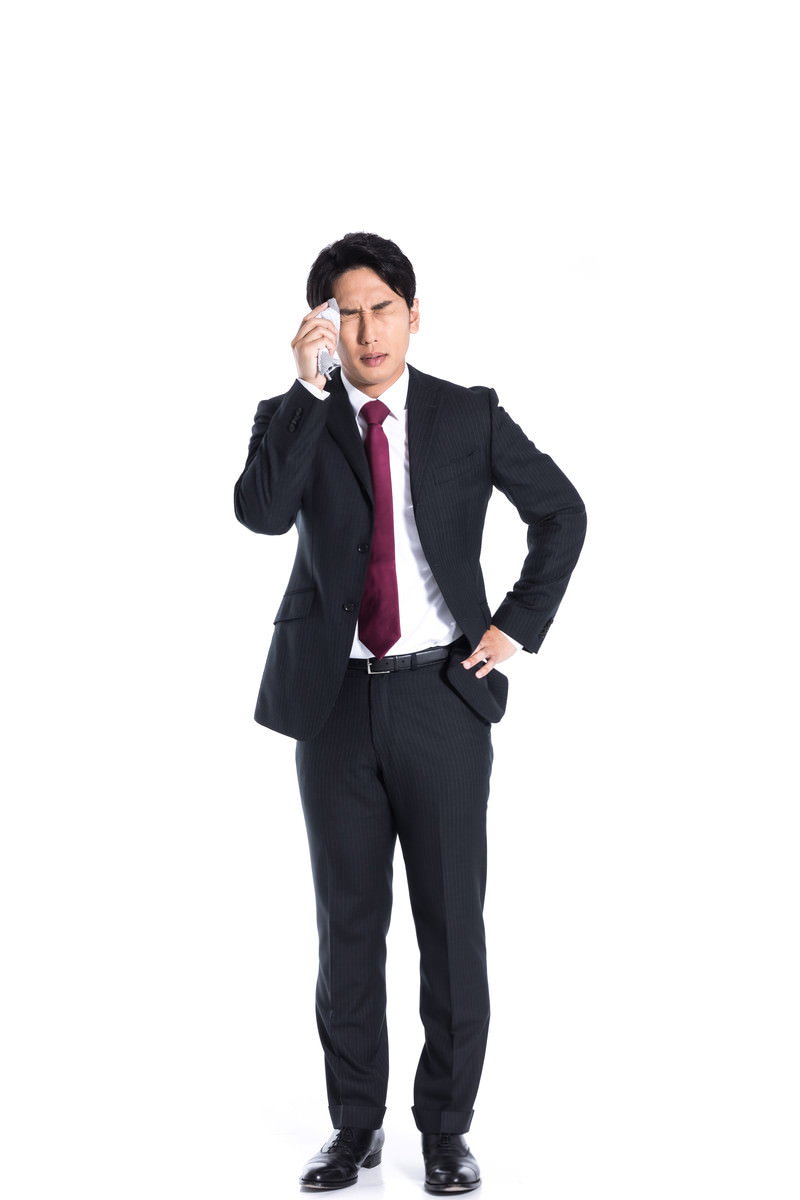 紺色のスーツに赤いネクタイを着た営業マンが白いハンカチで汗を拭いている様子［モデル：大川竜弥］