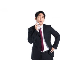 黒いスーツのサラリーマンがハンカチで汗を拭きながら営業の写真