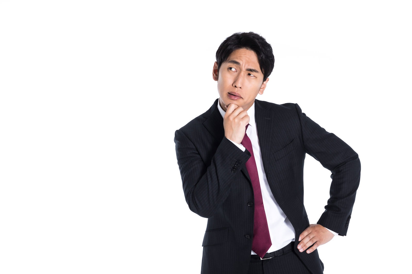 手を顔に当てて何かを盗み聞きしているスーツ姿の男性［モデル：大川竜弥］