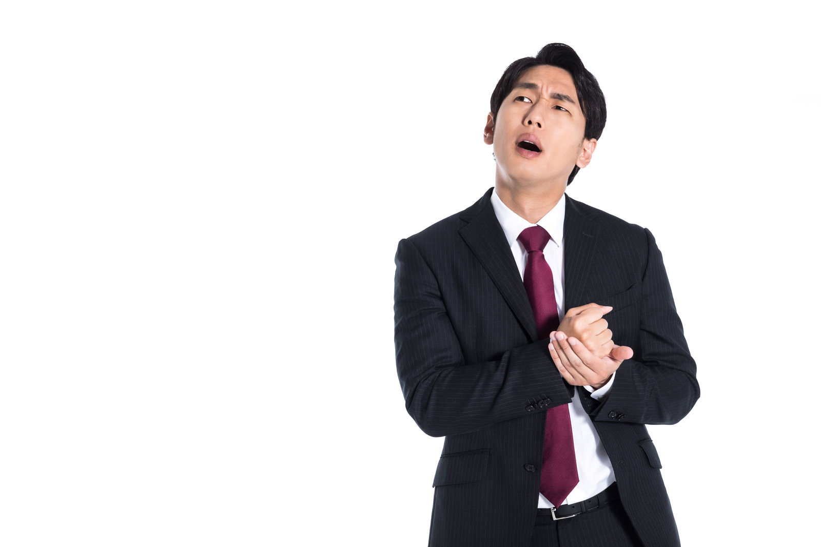 黒いスーツを着た新入社員が右手を胸に当てて上を見上げている［モデル：大川竜弥］