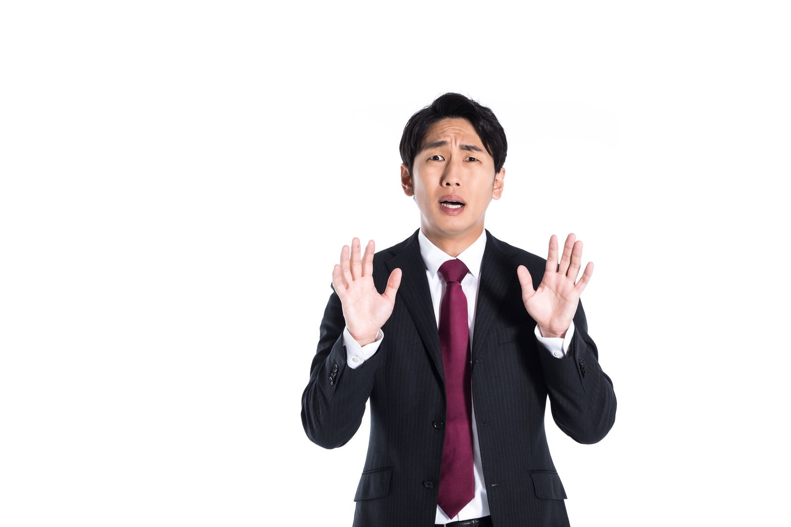 両手を上げて困惑した表情で口を開く濃紺スーツの男性［モデル：大川竜弥］