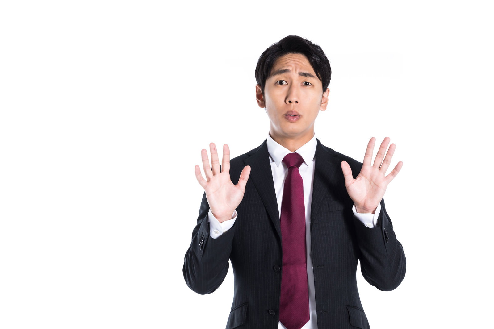 両手を上げて狼狽えた表情のスーツ姿の男性［モデル：大川竜弥］
