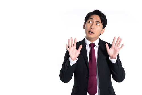両手を上げて狼狽える黒スーツの男性