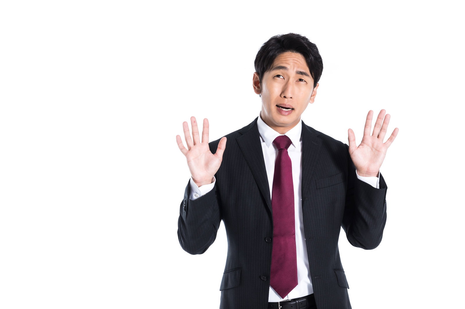 お手上げポーズで驚くスーツ男性［モデル：大川竜弥］